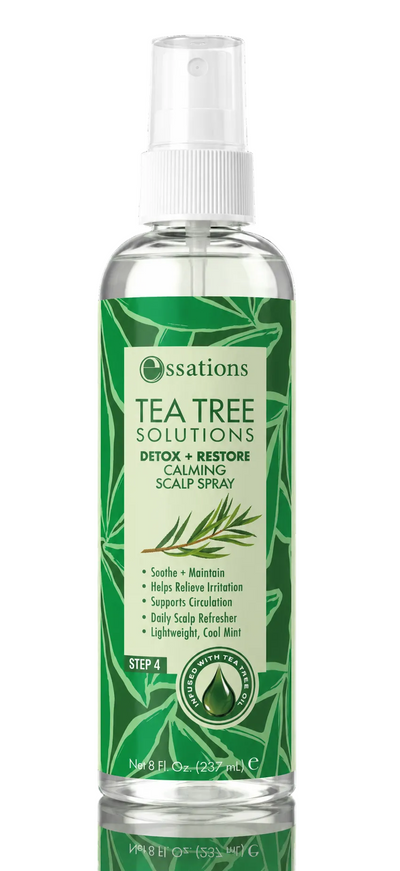 A bottle of Essations Tea Tree Solutions Detox + Restore Calming Scalp Spray on a solid black background with a reflection below. The bottle is clear, showing the liquid inside, and features a prominent green label with white text and illustrations of tea tree leaves.